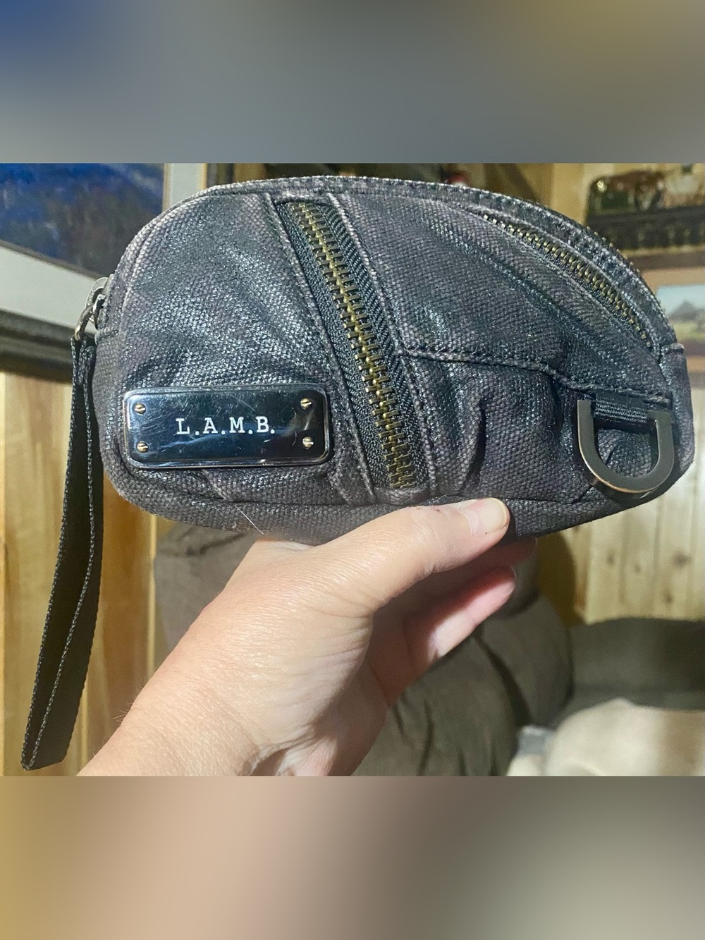 L.A.M.B. Dark textured wristlet with distinctive metal logo plaque on front